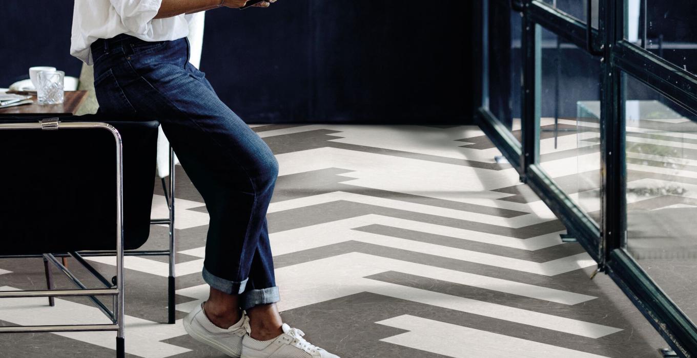 Obieta stojąca przy biurku na podłodze z paneli Creation 70 LL w dwóch kolorach zamontowanych w jodełkę